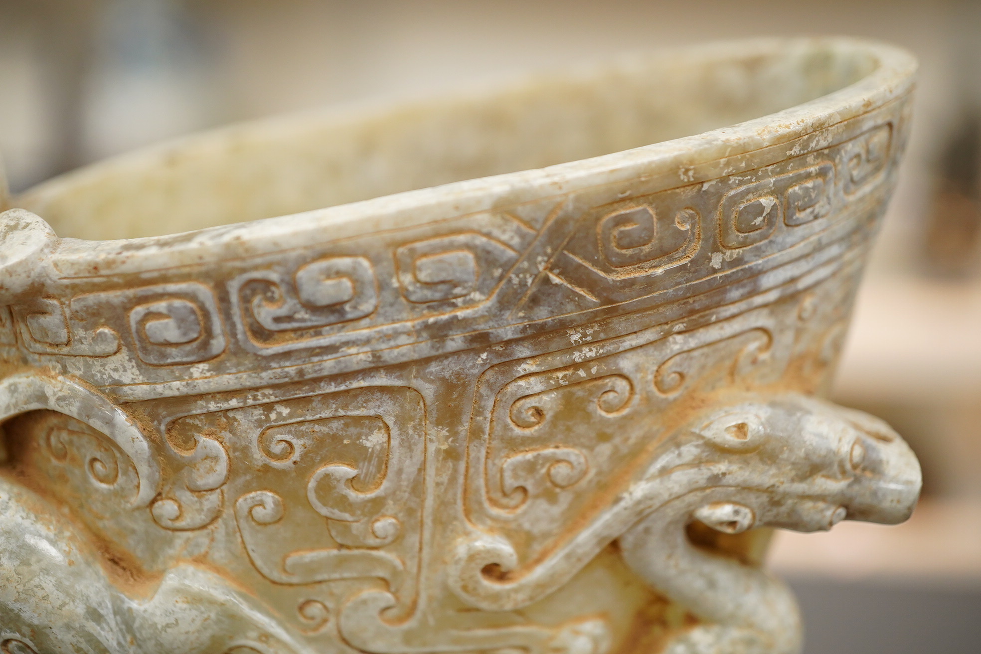 A large Chinese archaistic pale celadon and calcified jade rhyton, on a hardwood stand, 17.5cm high. Condition - fair to good.